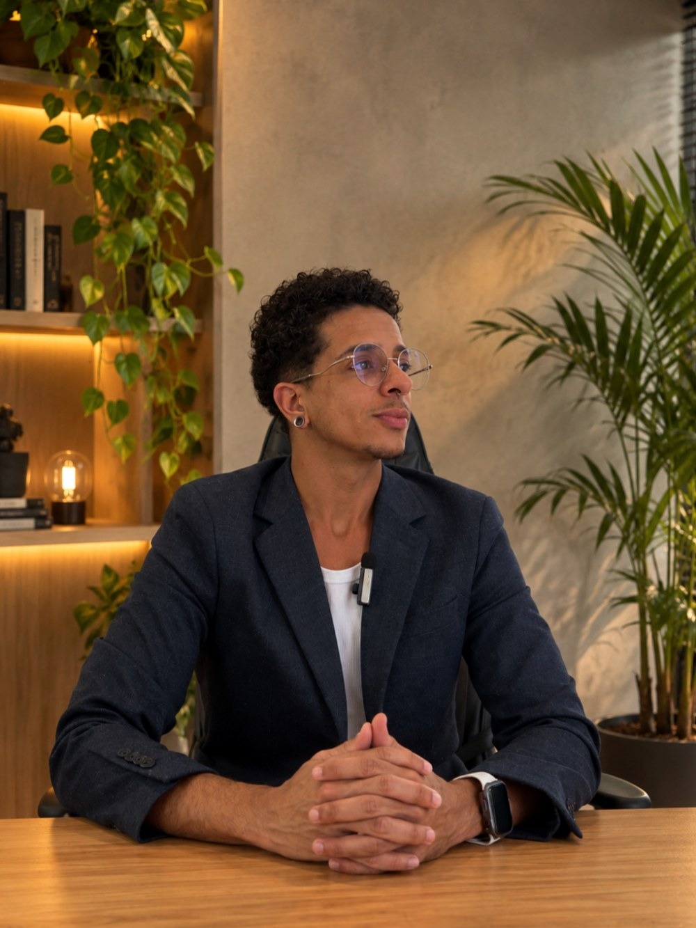 André Liberali sentado à mesa do consultório, com as mãos entrelaçadas, olhando para o lado